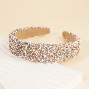 Macro detail of wide headband featuring hand-sewn rhinestones and faux pearls on a sponge base