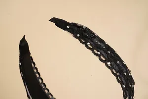 Detail van zwarte kanten haarband met geborduurde bloemen en glinsterende strassteentjes
