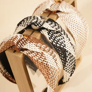 Detail of woven raffia headbands with resin rings displayed on a wooden stand