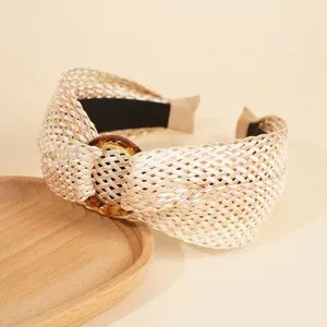 Detail of bohemian raffia weave headband with amber resin ring on a wooden tray