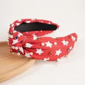 Close-up of red knotted headband with white stars, pearls and sparkling rhinestones