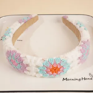 Close-up of handmade crochet headband with granny square floral patterns on a ceramic tray