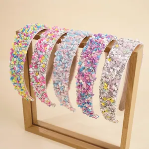 Detail von bonbonfarbenen Haarbändern mit Strass und Perlen auf einem Holzständer
