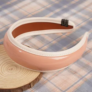 Dettaglio di cerchietto in pelle PU rosa con bordo bianco e trama di cucitura premium