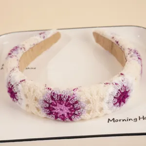 Close-up of crochet floral pattern on a cream knitted headband with purple gradient flowers