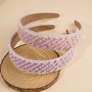 Detail von rosa und lila breiten Haarreifen mit Kunstperlen und Perlen auf Holzdeko