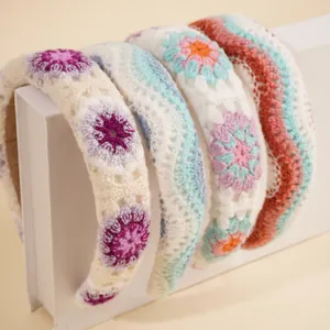 Close-up of four knitted boho headbands with floral and wave patterns on books