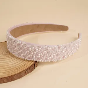 Nahaufnahme eines rosa Haarreifens mit weißen Perlen auf einem Holzständer