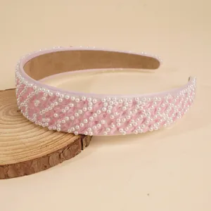 Detail eines rosa breiten Haarreifs mit Perlen und Kristallen auf einer Holzscheibe