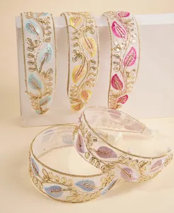 Detail of embroidered leaf headbands with sequins on organza fabric and gold trim