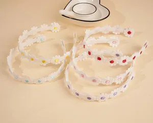 Close-up of white lace headband with embroidered daisies and colorful flower details