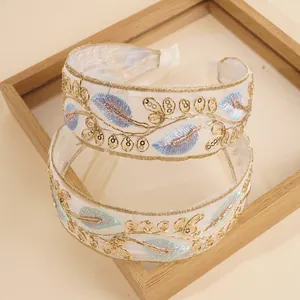 Detailed embroidery of gold leaves and blue sequins on a bohemian white organza headband