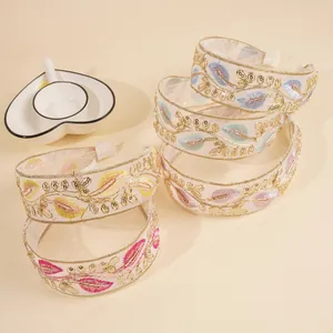 Close-up of embroidered organza headbands with colorful leaf patterns and golden thread