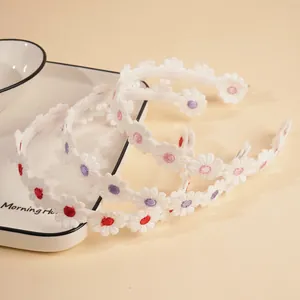Detail showing high-quality embroidered daisy flowers on a white non-slip headband set