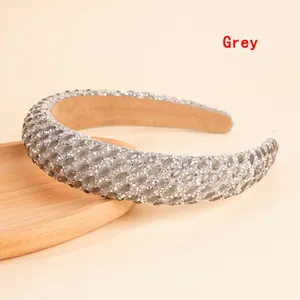 Macro detail of grey rhinestone padded headband on a wooden tray with sparkling crystals