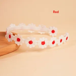 Close-up of white daisy embroidery with red centers on a non-slip floral headband