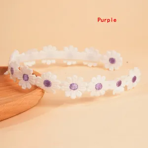 Close-up of embroidered white daisies with purple centers on a non-slip headband