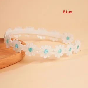Detail showing embroidered white daisies with blue centers on a non-slip white headband