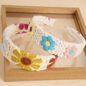 Detail eines handgefertigten Boho-Häkelstirnbands mit filigranem Strickmuster und Blumen