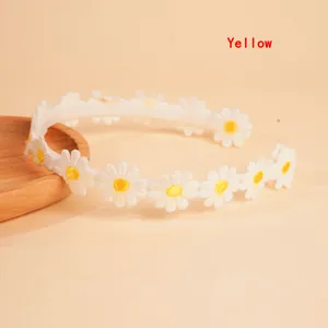 Detail shot of embroidered white daisy flower headband with yellow accents on a beige background