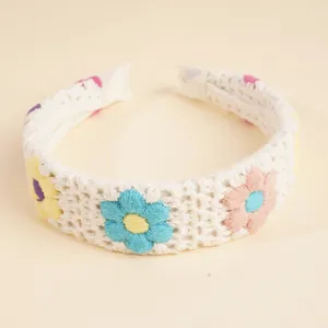 Nahaufnahme eines weißen Häkel-Stirnbandes mit bunten bestickten Boho-Blumenmustern
