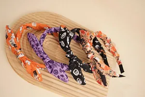 Detail von vier Halloween-Schleifen-Haarbändern mit Kürbis- und Geisterprint auf Holz