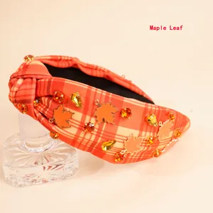 Detailaufnahme von kariertem Haarreif mit Ahornblatt-Anhängern und orangefarbenen Strass