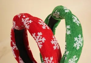 Detail von roten und grünen Samt-Weihnachtsstirnbändern mit Pailletten-Schneeflocken-Design