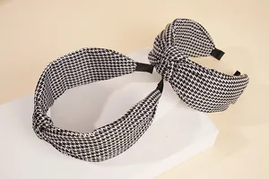 Détail de deux serre-têtes à motif pied-de-poule avec un nœud en tissu noir et blanc
