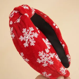 Detailaufnahme von rotem Samt-Haarreif mit weißen Pailletten-Schneeflocken und Knotendesign