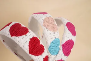 Gros plan du bandeau tricoté blanc avec motifs de cœur au crochet colorés et texture