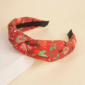 Détail d'un serre-tête de Noël noué en tissu rouge avec motifs de rennes et de neige