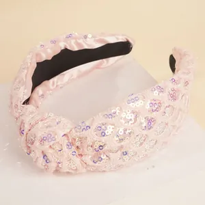 Detailed close-up of a pink sequined wide knotted headband with shimmering fabric texture