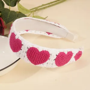 Gros plan d'un bandeau en tricot blanc avec des motifs de cœur roses au crochet