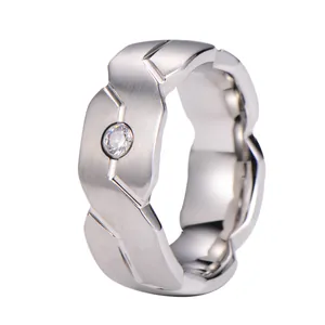 Brushed tungsten ring with geometric faceted edges and a center set clear gemstone