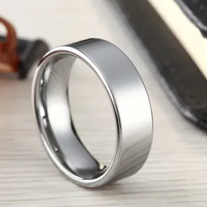 Polished silver tungsten steel wide flat band ring with a mirror finish on wood