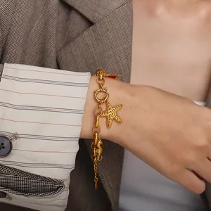 Goldenes Edelstahl-Armband mit Seestern- und Seepferdchen-Anhänger am Handgelenk