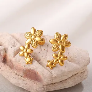 Orecchini a tre fiori in acciaio inossidabile dorato su uno sfondo di pietra rosa naturale
