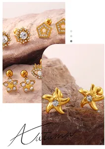 Gros plan sur des boucles d'oreilles barbell dorées avec cristaux et formes d'étoiles