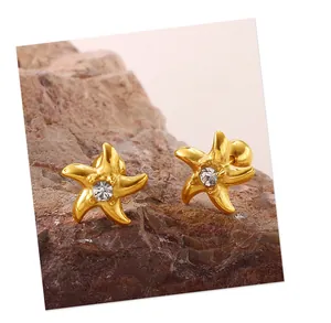 Vue macro de boucles d'oreilles étoile de mer dorées avec cristal sur une pierre naturelle