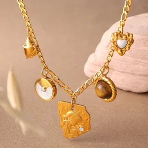Collier multi-pendentifs vintage doré avec œil de tigre et coquillages sur fond de sable