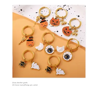 Macro shot of Halloween themed 18K gold earrings with pumpkin, ghost and skull charms