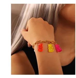 Goldenes Armband mit drei bunten Gummibärchen-Anhängern in Orange, Gelb und Rosa