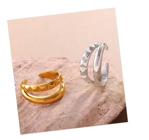 Detalle de pendientes sin agujero oro y plata con textura piramidal en fondo rosa