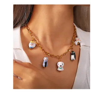 Détail d'un collier chaîne dorée orné de cinq breloques animaux en céramique colorée