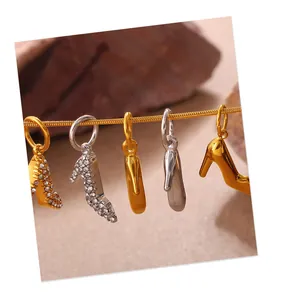 Dettaglio di ciondoli a forma di scarpa con tacco in oro e argento con strass lucidi