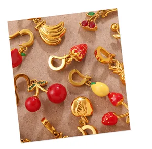 Close-up of colorful fruit pendants with enamel finish and gold plating on paper background