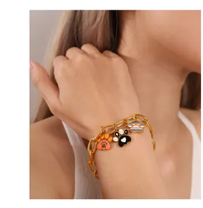 Detail of a gold chain bracelet featuring colorful enamel animal paw print charms