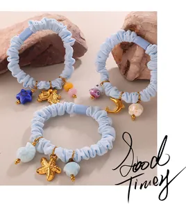 Detail of light blue scrunchies with golden sea star and shell charms on stone