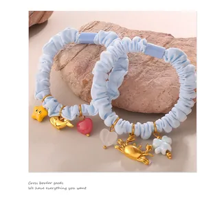 Close-up of ocean-themed scrunchies with whale and crab charms on natural stone